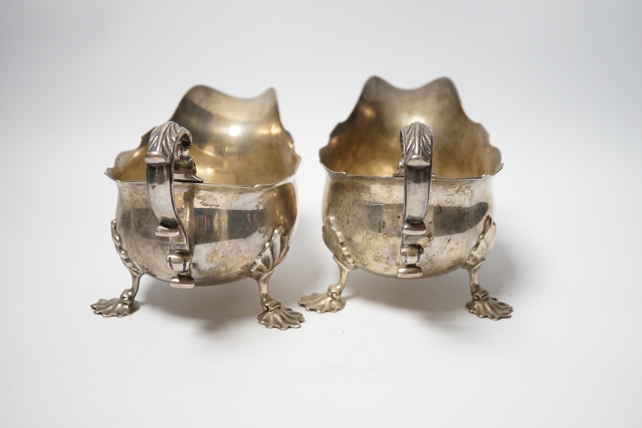 A pair of Edwardian silver sauce boats with shell knees, on three fluted feet, Carrington & Co, London, 1902, length 20.8cm, 33.9oz.